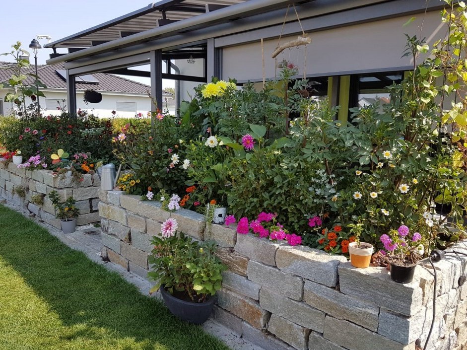 Zipscreen an Terrassendach vor Blumenbeet