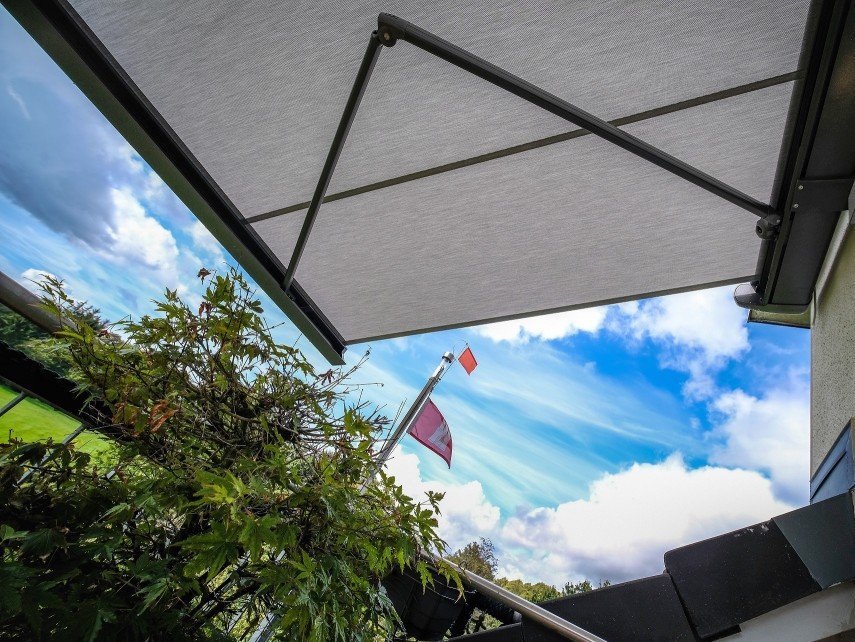 Markise mit hellem Markisentuch vor blauem Himmel