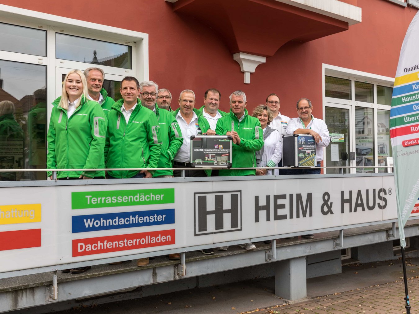 HEIM & HAUS Teamfoto der Verkaufsleitung Kaiserslautern mit 2 HEIM & HAUS Koffern