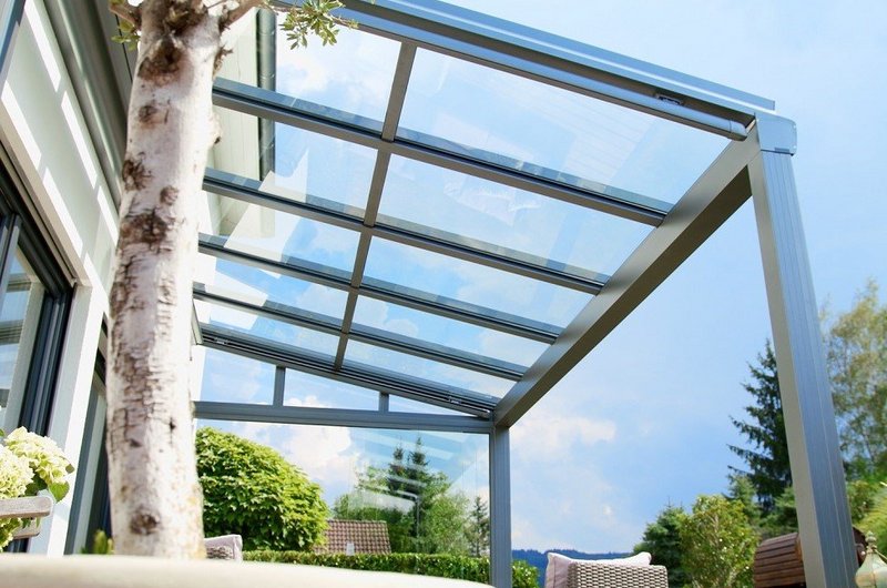 Transparentes Terrassendach mit Wetterschutzelement vor Himmel