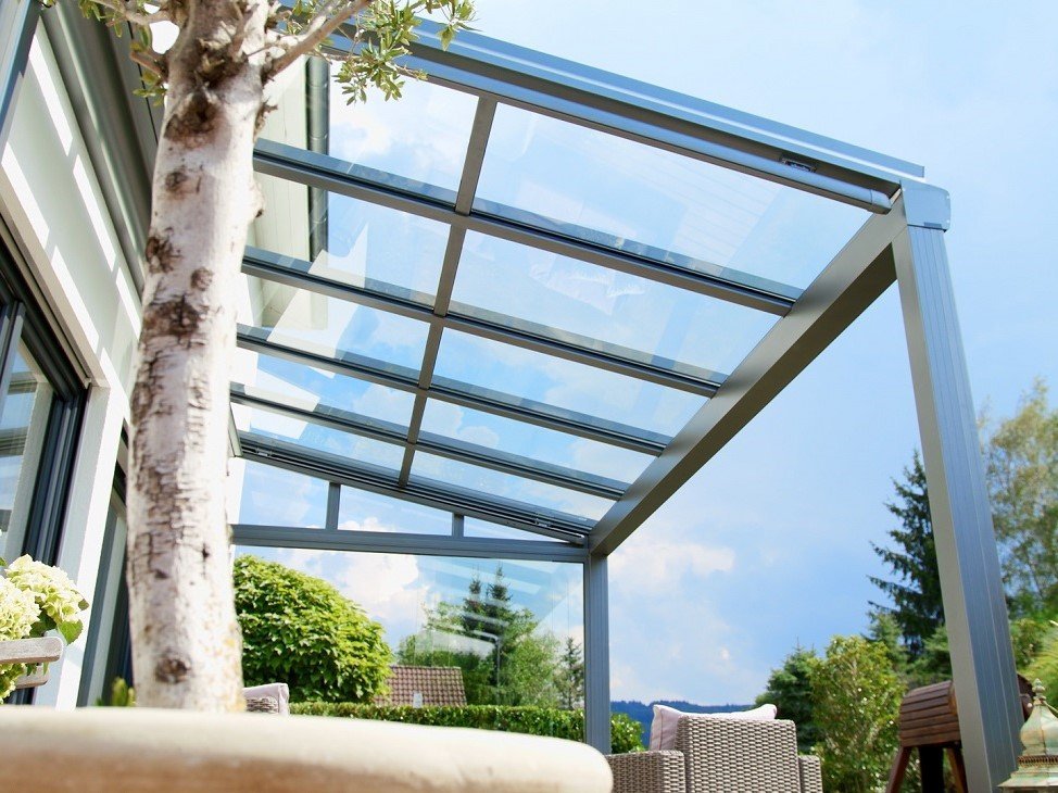 Transparentes Terrassendach mit Wetterschutzelement vor Himmel