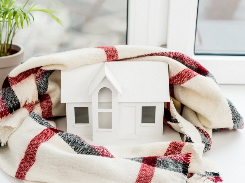 Energieeinsparung im Winter Modellhaus mit Schal auf Fensterbank