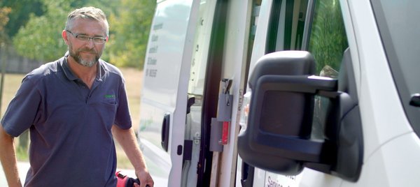 Mann mit Werkzeug in der Hand vor einem Auto