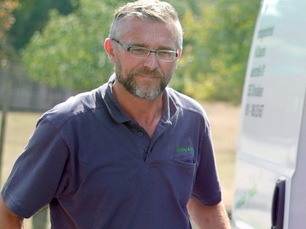 Mann mit Werkzeug in der Hand vor einem Auto