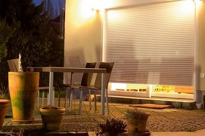 Sichtschutz und Energiesparen durch smarte Rollladensteuerung Rollladen beleuchtet vor Terrassentür bei Nacht