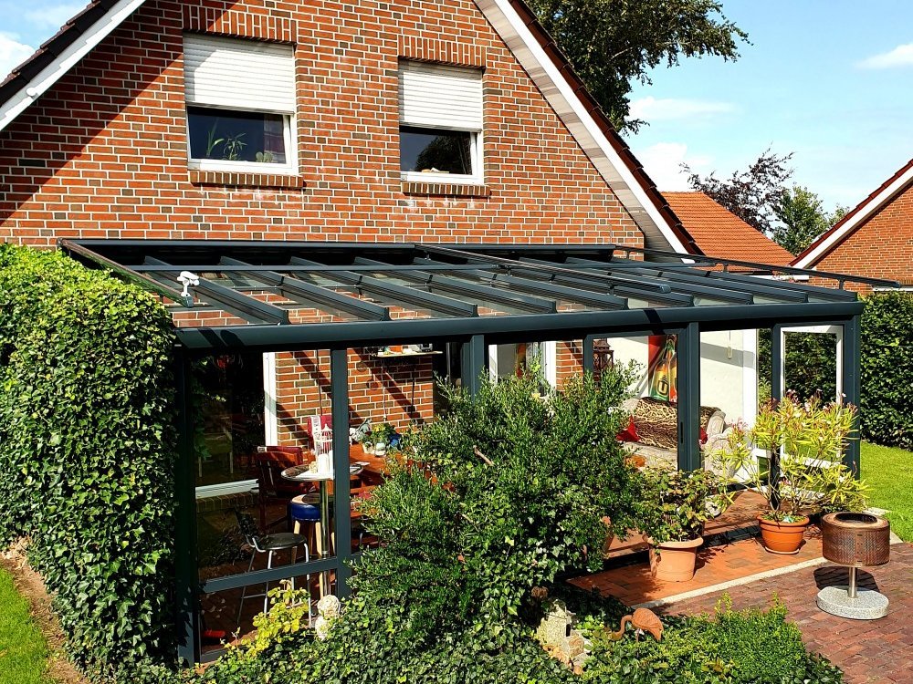 Gläsernes Terassendach an roter Fassade