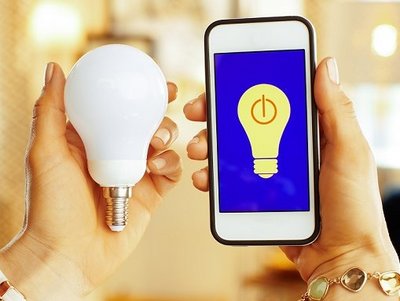 Frauenhände halten Glühbirne und Smartphone