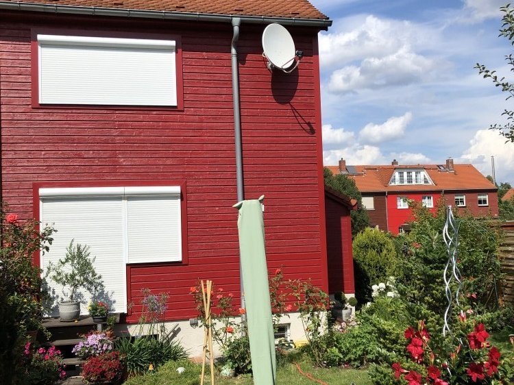 Rollladen mit weißem Rollladenpanzer an roter Hausfassade