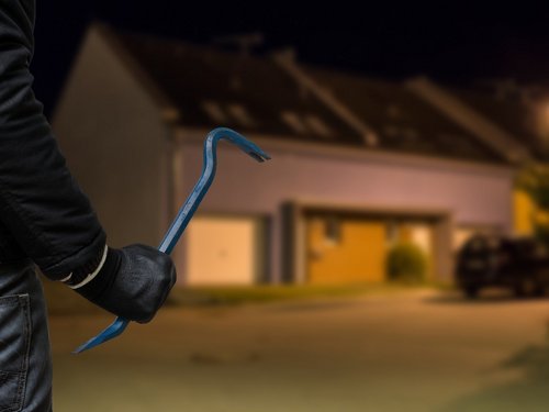 Einbrecher mit Brecheisen vor Haus bei Nacht