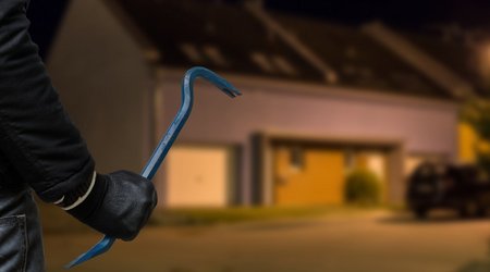Einbrecher mit Brecheisen vor Haus bei Nacht