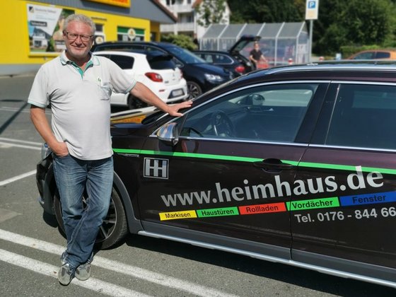 HEIM & HAUS Bezirklsleiter Herr Roedel der Verkaufsleitung Bamberg neben einem HEIM & HAUS Auto