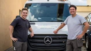 Zwei HEIM & HAUS Handwerker, die an ihrem Fahrzeug lehnen