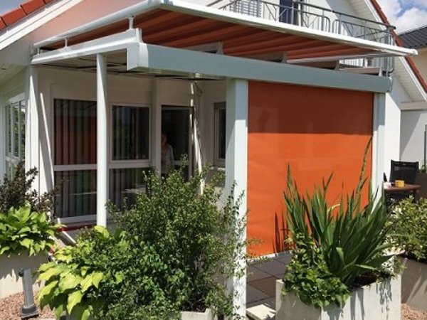 Textilscreens schützen Außenbereiche vor Sonneneinstrahlung Zipscreen mit orangenem Screen-Stoff an Terrassendach