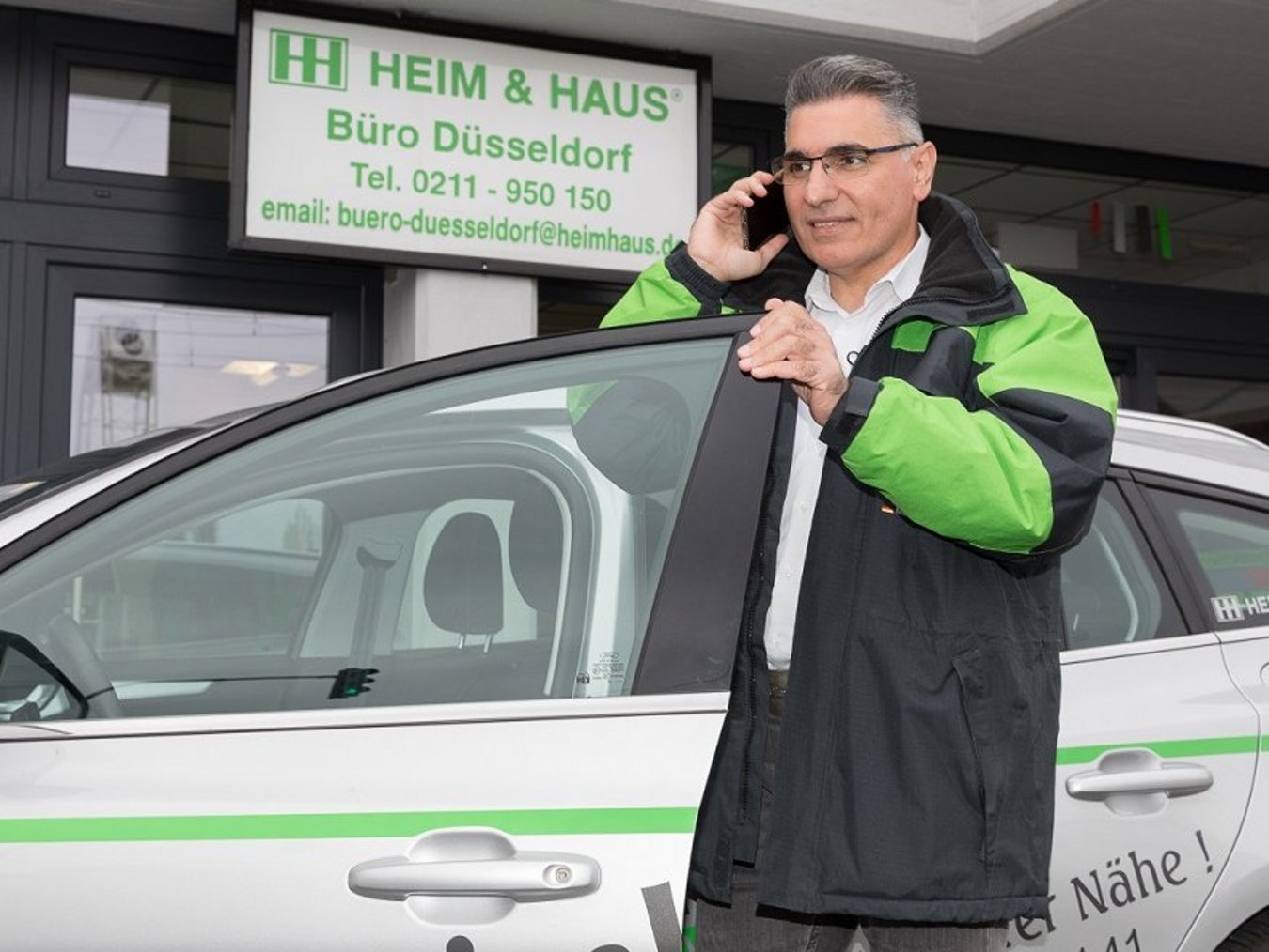 HEIM & HAUS Fachberater der Verkaufsleitung Düsseldorf an einem Handy im Auto
