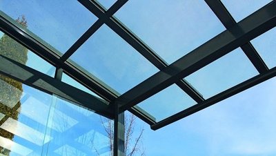 Gläsernes Terrassendach vor blauem Himmel von unten