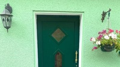 Dunkelgrüne Haustür auf hellgrüner Fassade