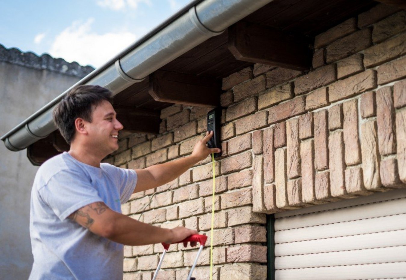 Handwerker, der etwas an die Außenwand montiert