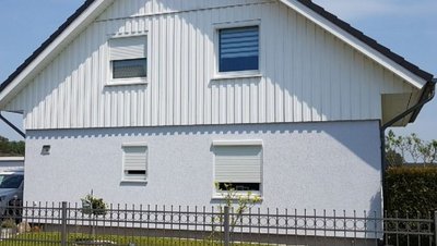 Haus mit Rolladen in zweigeteilter Fassade