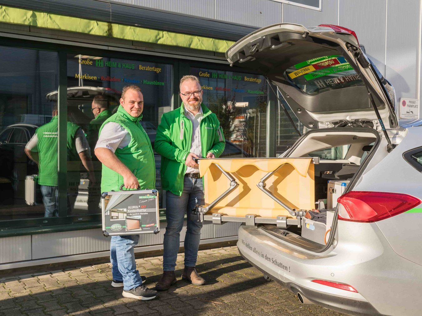 HEIM & HAUS Fachberater der Verkaufsleitung Aachen an einem Auto mit verschiedenen Exponaten