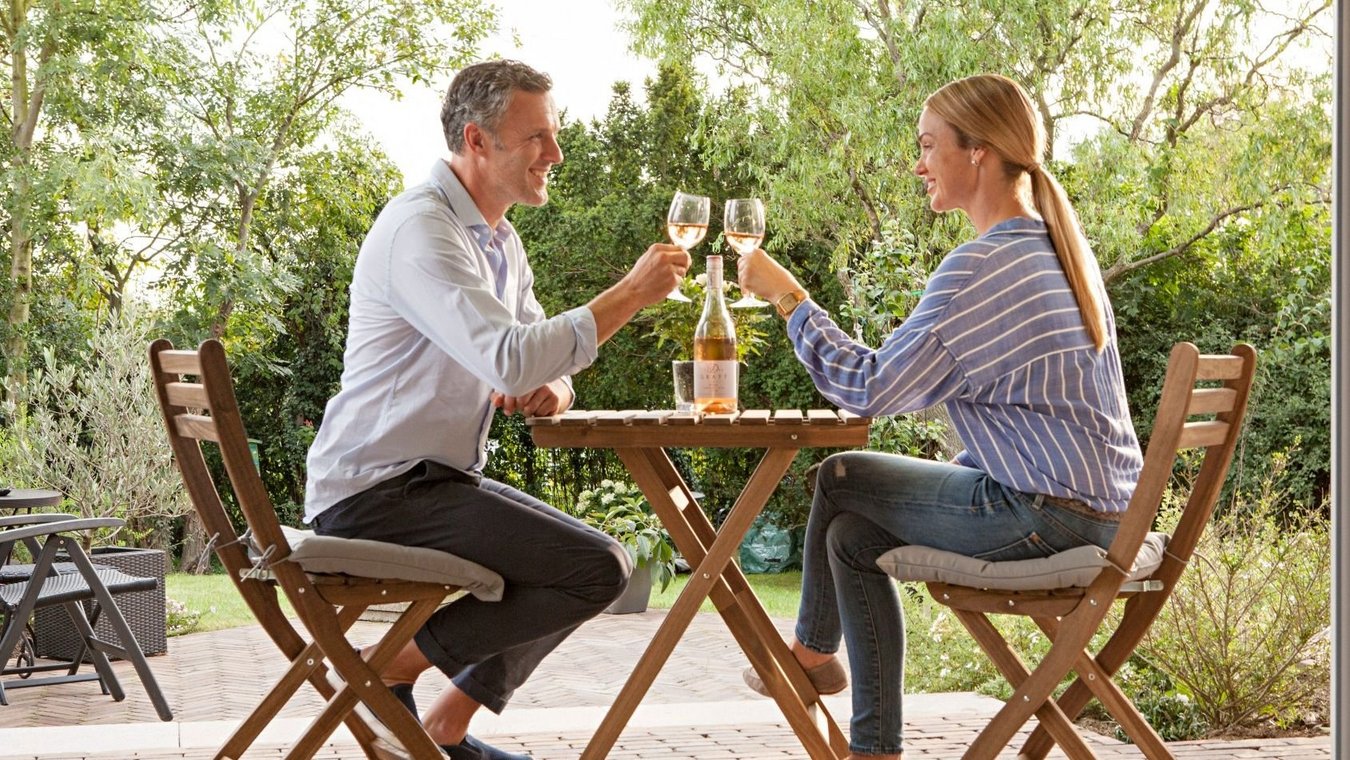 HEIM & HAUS Stock Material von einem Pärchen die an einem tisch sitzen und anstoßen