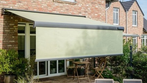 Ein VarioVolant hält tiefstehende Sonnenstrahlen ab Grüne Markise mit ausgefahrenem Volant vor Terrassentür