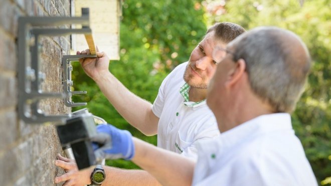 zwei Handwerker, die etwas an eine Wand montieren