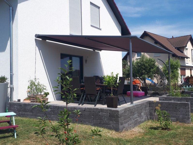 Dunkle Pergolamarkise an weißer Hausfassade