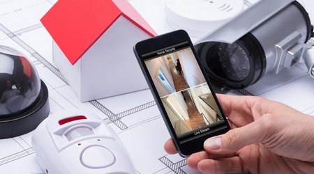 Hand hält Handy mit Videoüberwachung eines Gebäudes