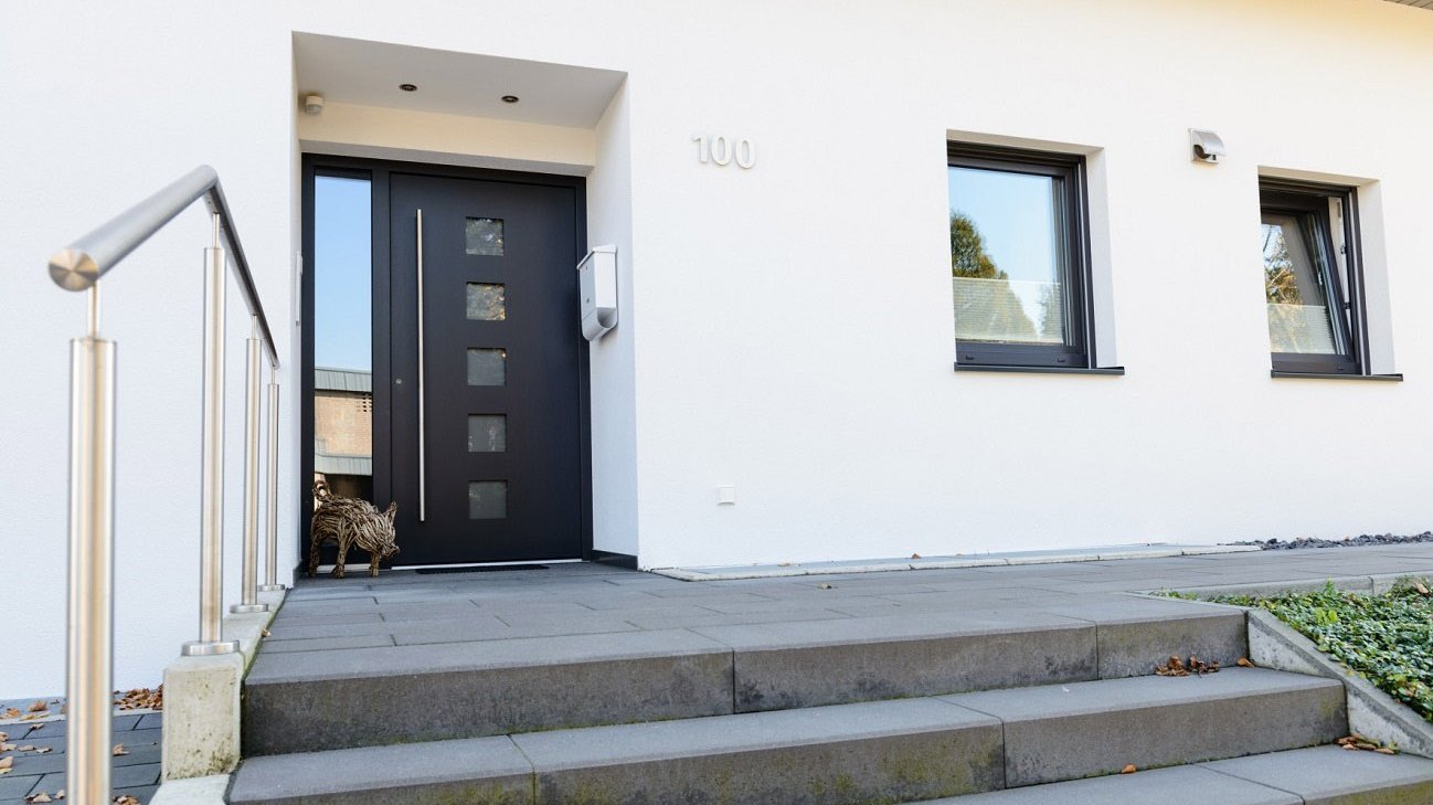 Dunkle Haustür mit Glasornamenten und Griffstange