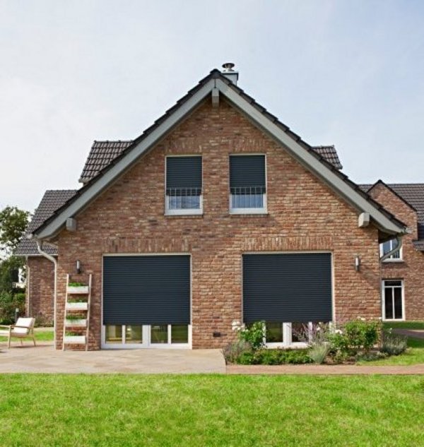 Frontalansicht Haus mit bodentiefen Fenstern und halb geschlossenen Rollladen