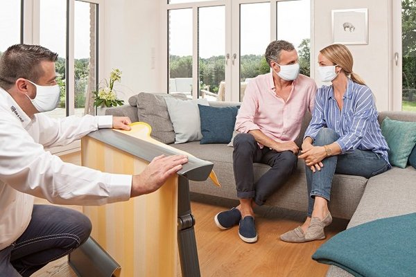 Fachberater berät Paar zuhause mit Masken und Abstand