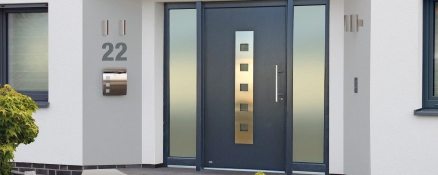 Dunkle Haustür mit Edelstahlornamenten und Seitenteilen aus Glas