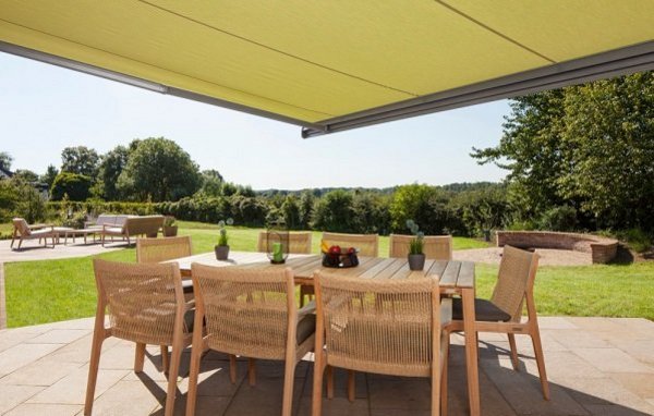 Ein Sonnenschutz klimatisiert den Außenbereich Gelbe Markise über Tisch mit Stühlen auf Terrasse