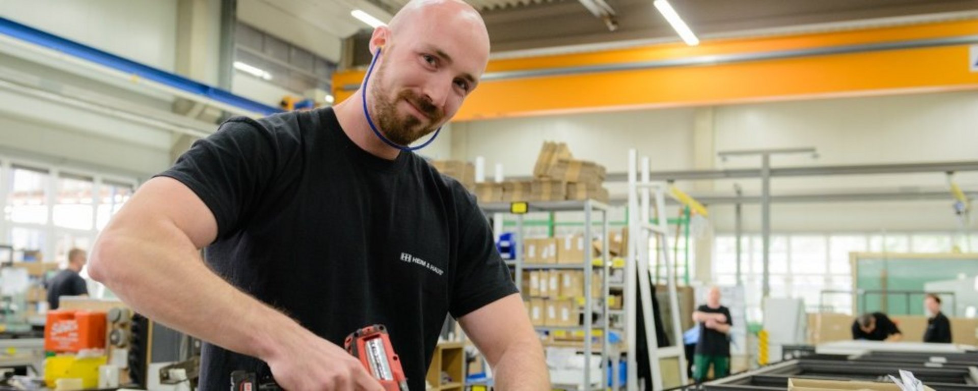 HEIM & HAUS Mann mit Akkuschrauber in der Hand, der in die Kamera lacht