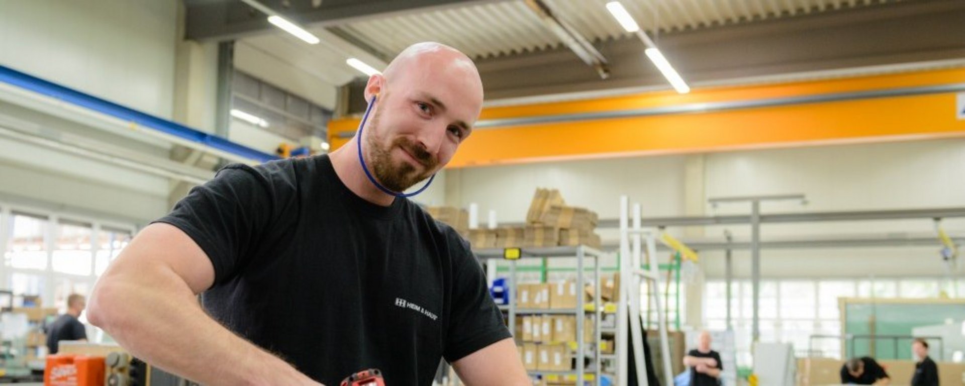 Mann mit Akkuschrauber in der Hand, der in die Kamera lacht