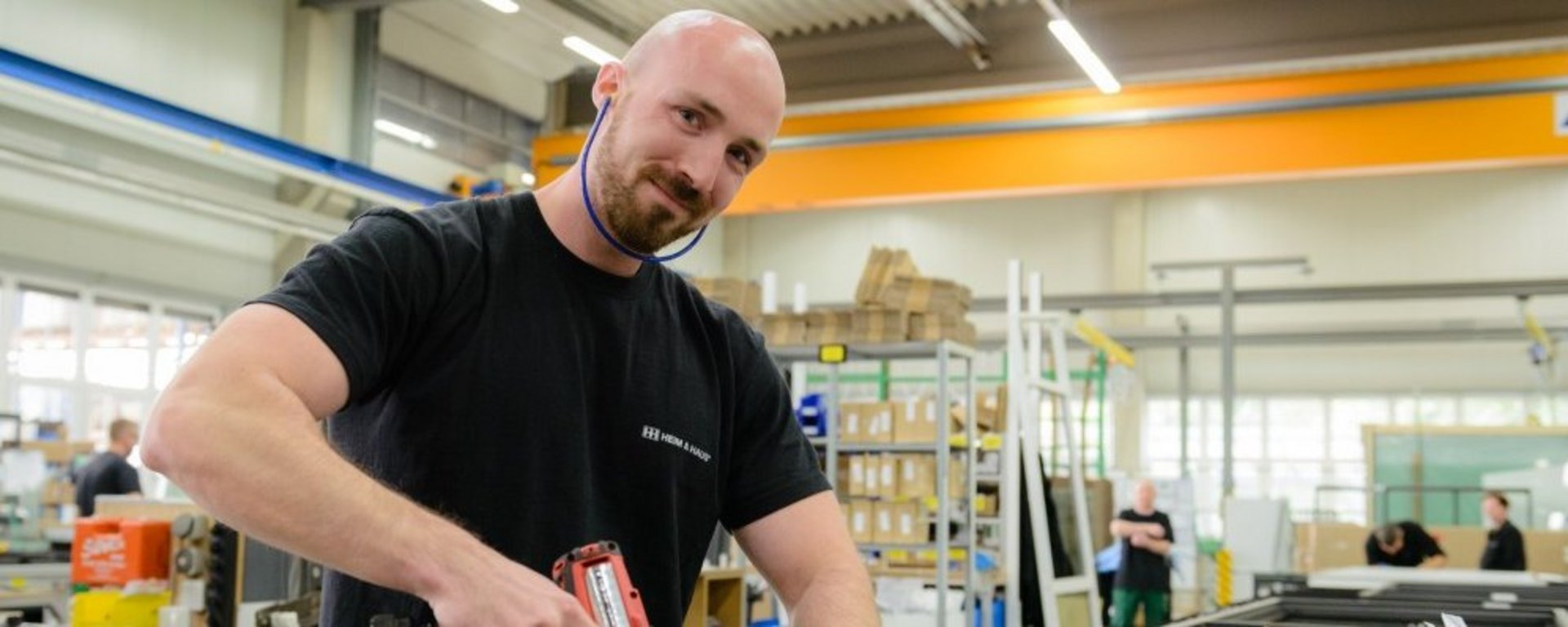 Mann mit Akkuschrauber in der Hand, der in die Kamera lacht