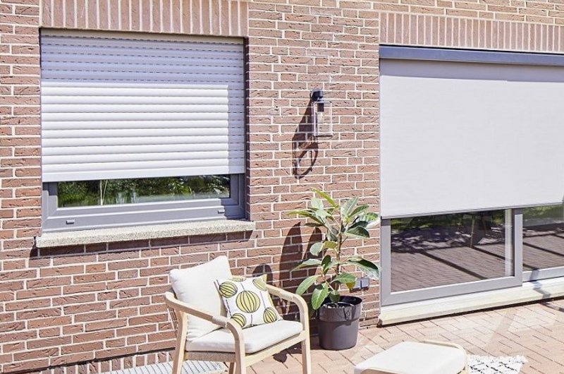 Fassade mit Rollladen und Zipscreens vor Fenstern