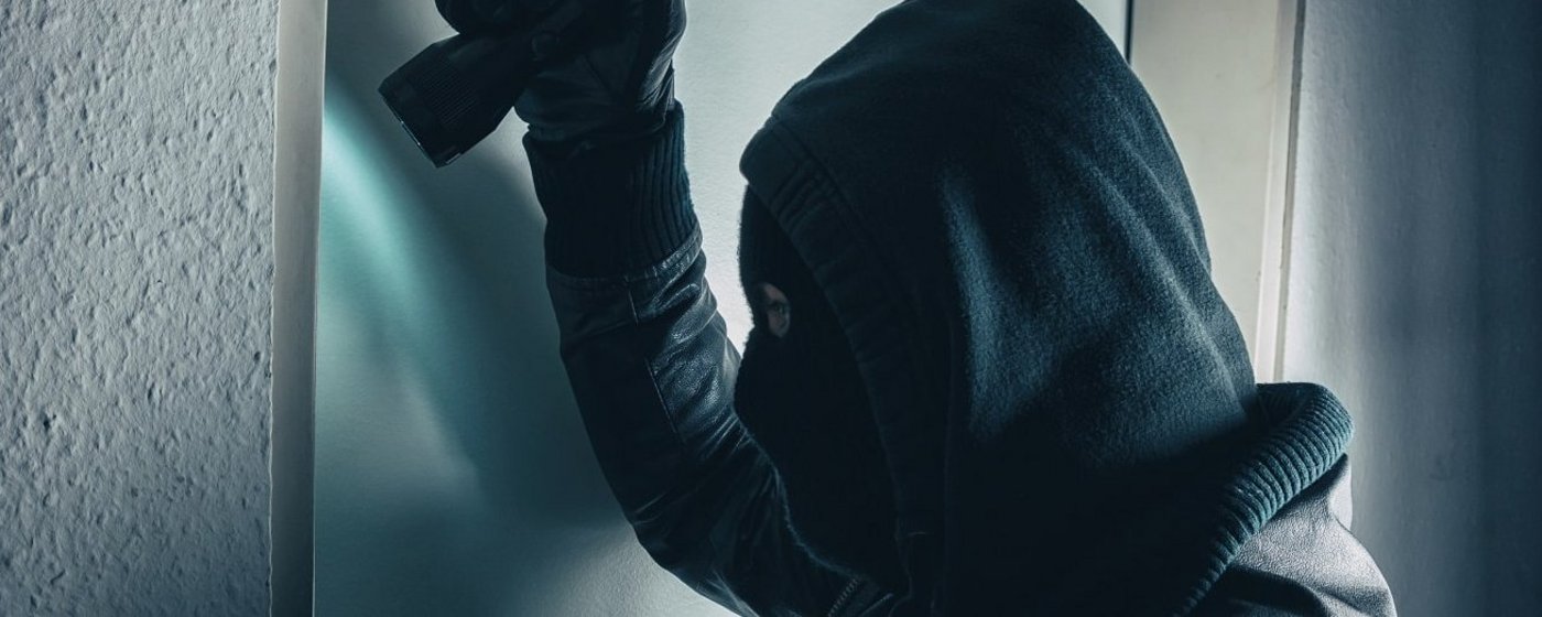 Einbrecher mit Taschenlampe untersucht Tür 
