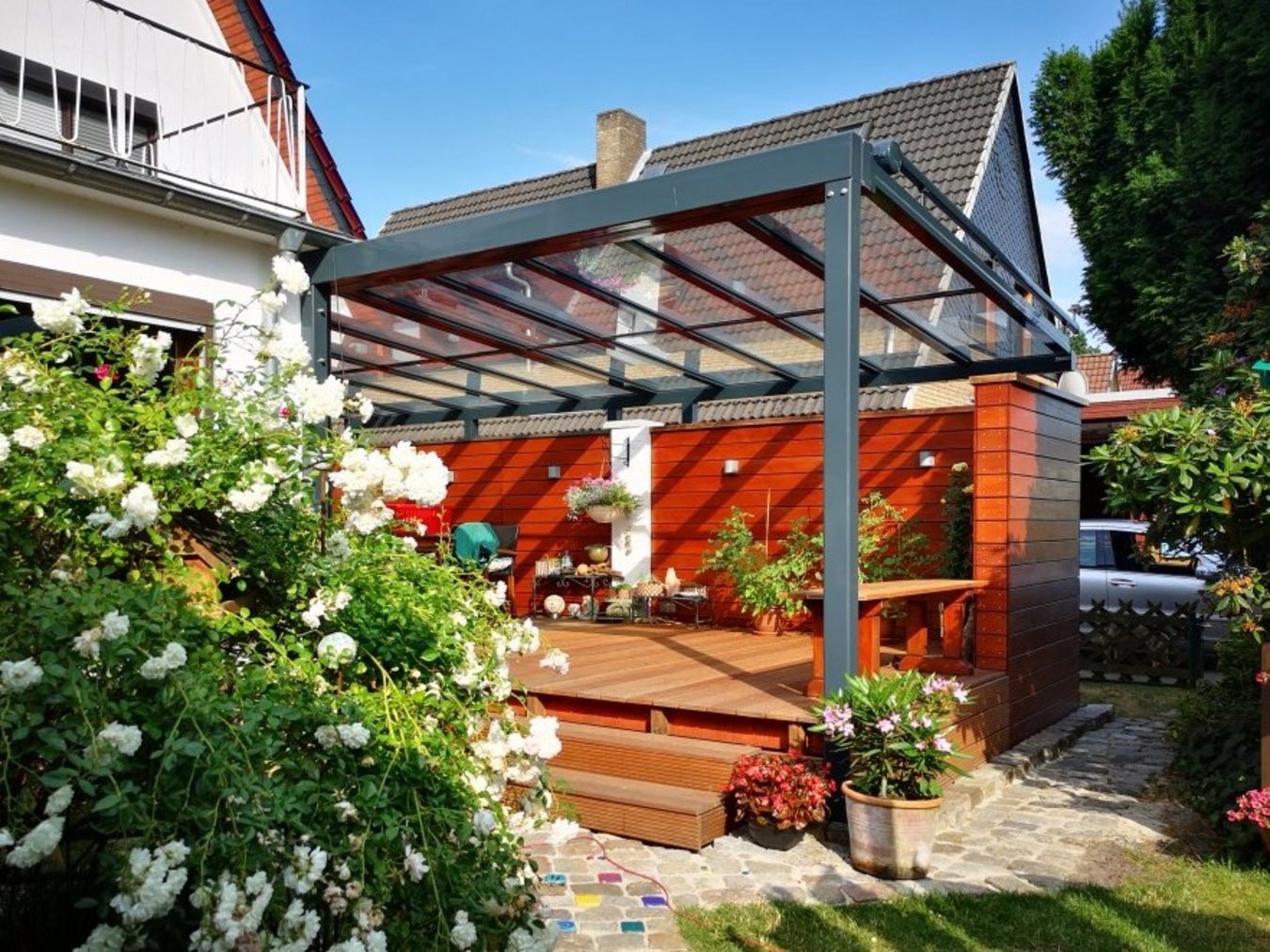 Gläsernes Terrassendach über Holzterrasse